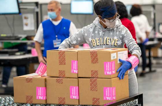 Warehouse workers packing up shipping boxes with Moderna Supply Kits inside