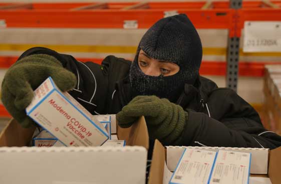 McKesson employee wearing winter gloves, hat and mask indoors while cold-packing the Moderna vaccine.<br>  <p>&nbsp;</p>  