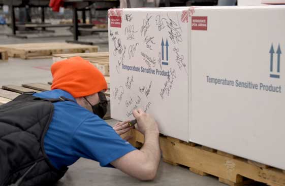 McKesson employee adding his signature to a box of Johnson and Johnson vaccines for shipment.