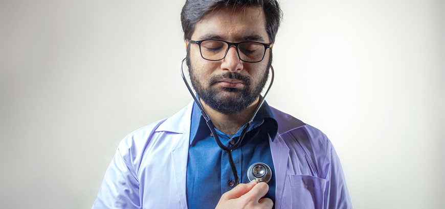 A doctor with a stethoscope listening to his own heartbeat