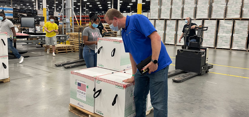 A man looking at a pallet of boxes inside a distribution center