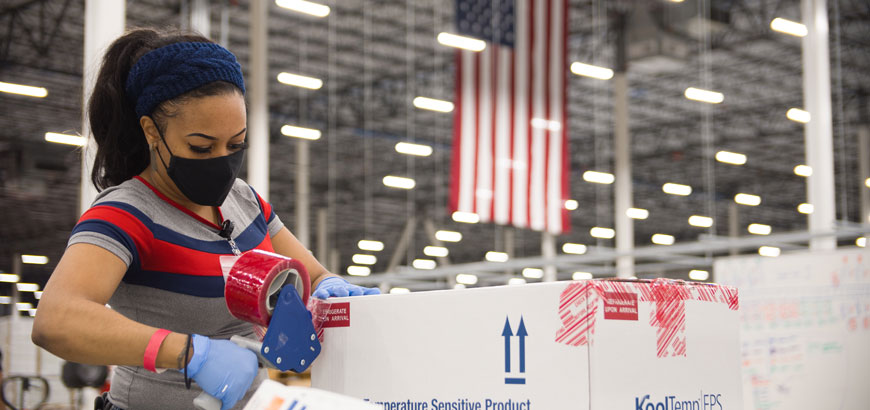 A worker taping boxes shut in a distribution center