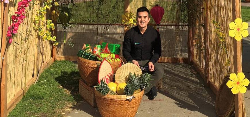A person sitting behind two large wicker baskets containing fruit and gifts