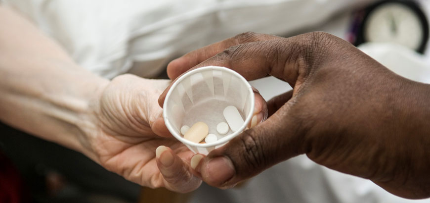 Close up of hands as one person hands another medication.