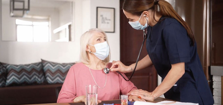 A nurse checks on an elderly patient during a home visit