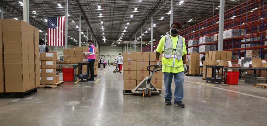 An employee pulling a pallet of boxes in a distribution facility