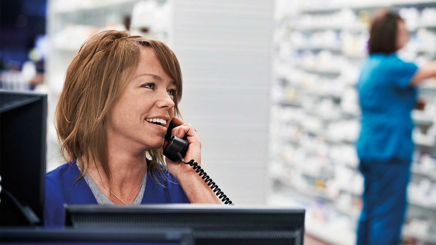 A pharmacy worker talking on the phone