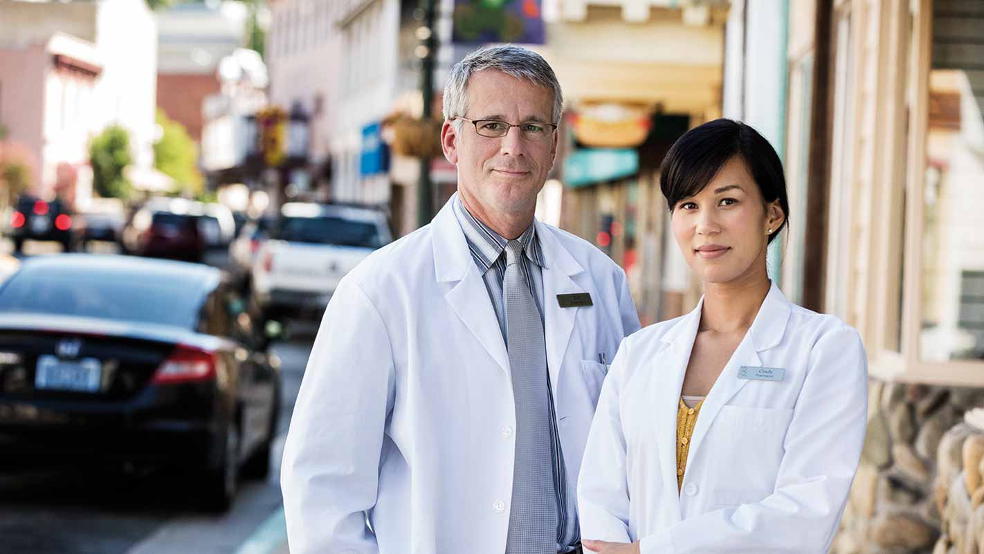 Two pharmacists standing outside a pharmacy building