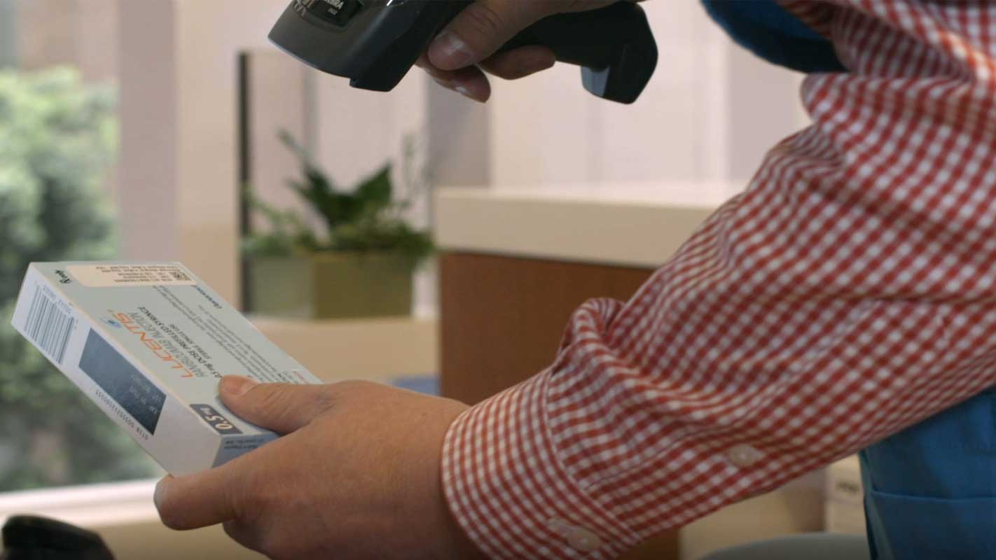 Hands use handheld scanner to scan medication<br>  