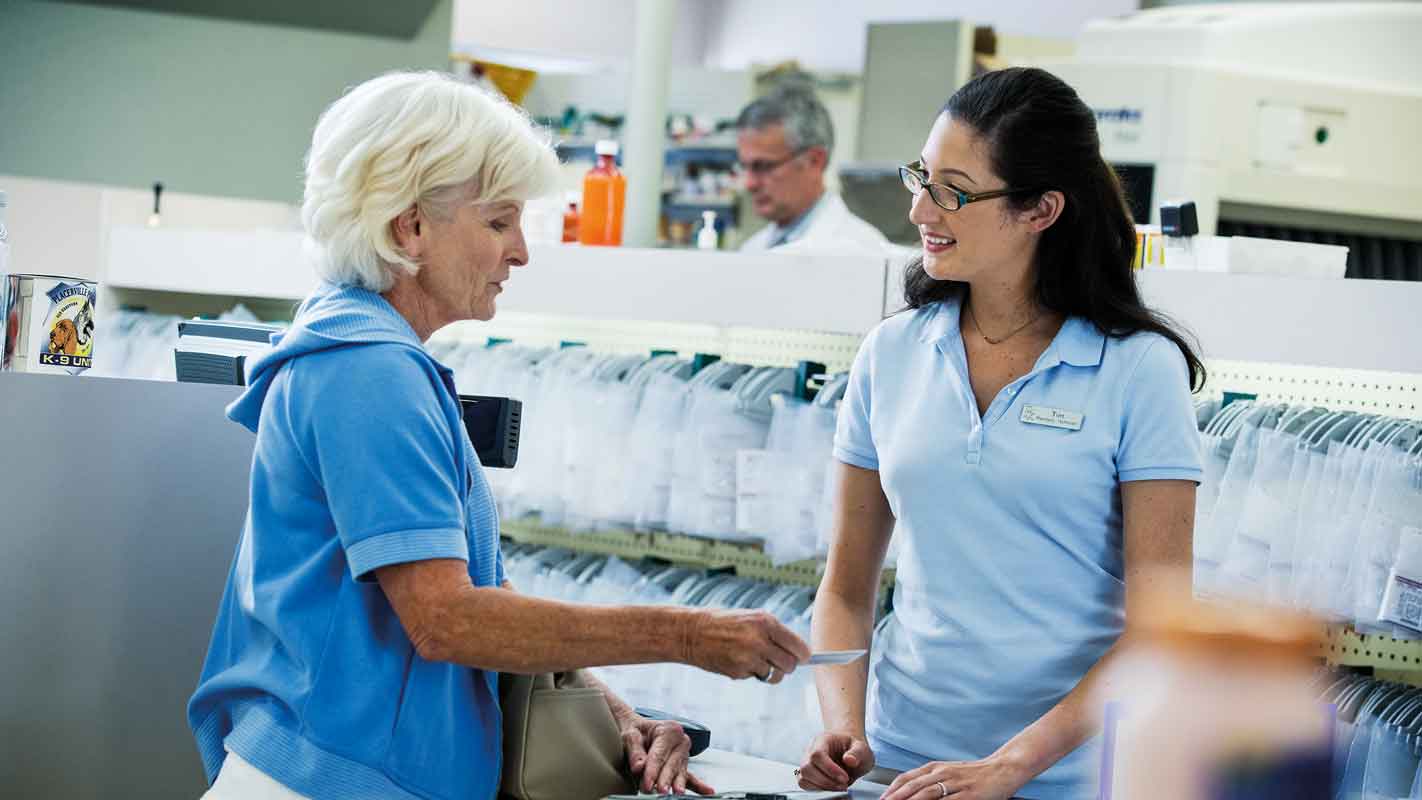 A pharmacy worker speaking with a customer